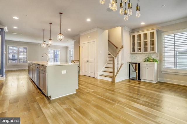 kitchen featuring tasteful backsplash, hanging light fixtures, light hardwood / wood-style floors, and ornamental molding