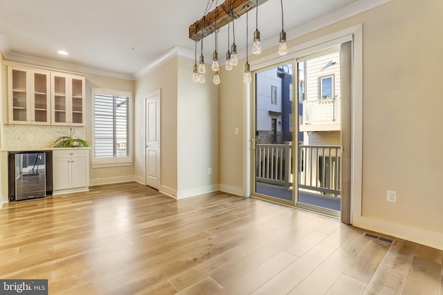 unfurnished dining area with wine cooler, a healthy amount of sunlight, and light wood-type flooring