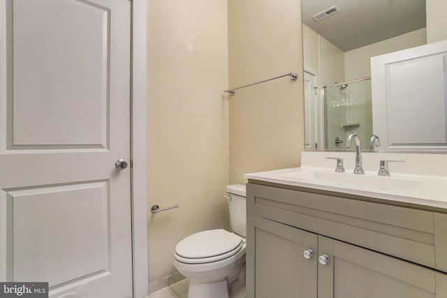 bathroom featuring tile patterned flooring, vanity, a shower with shower door, and toilet