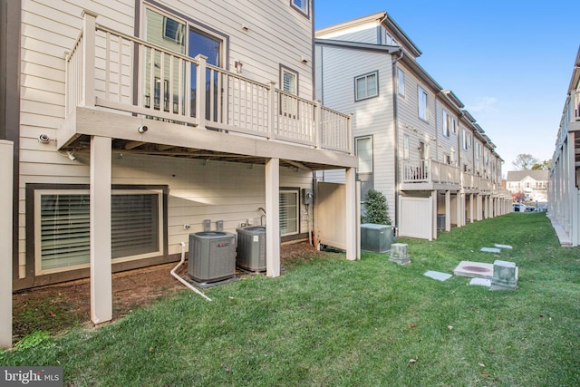 rear view of house featuring cooling unit and a lawn