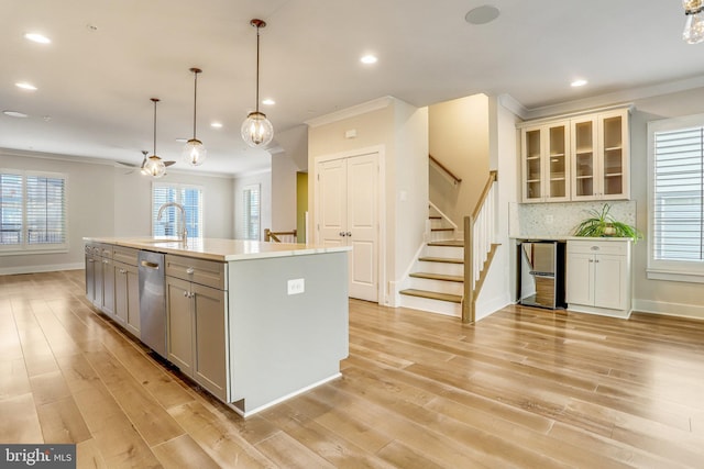 kitchen with a center island with sink, dishwasher, backsplash, and light hardwood / wood-style flooring