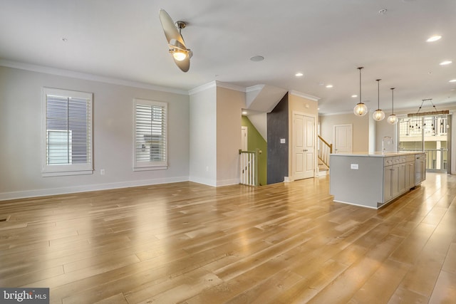 unfurnished living room with sink, light hardwood / wood-style floors, and ornamental molding