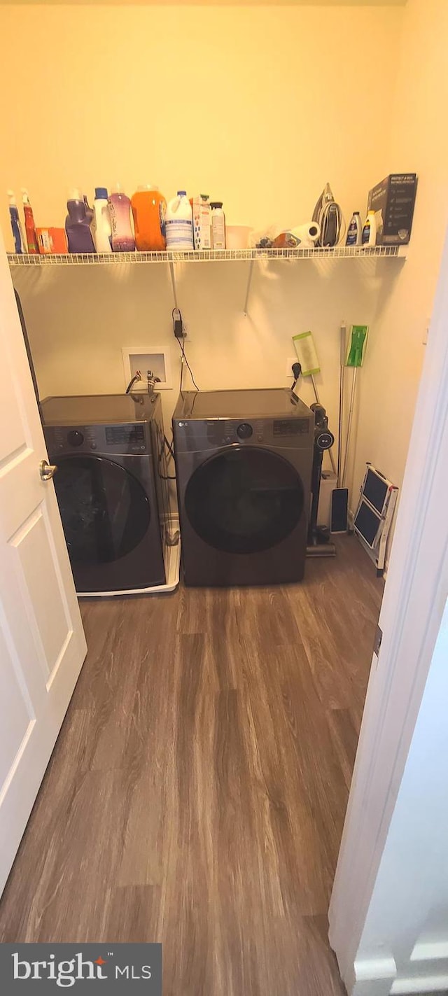 clothes washing area with washing machine and dryer and dark hardwood / wood-style flooring