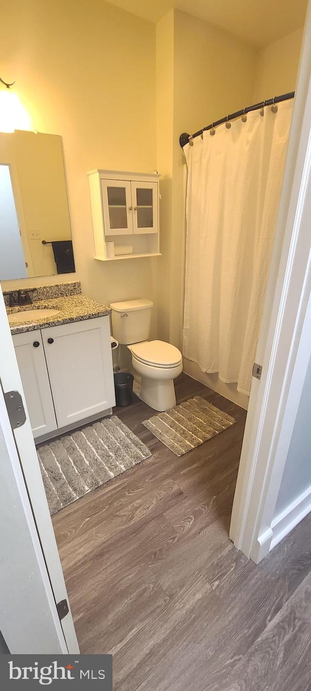 bathroom featuring a shower with shower curtain, hardwood / wood-style floors, vanity, and toilet