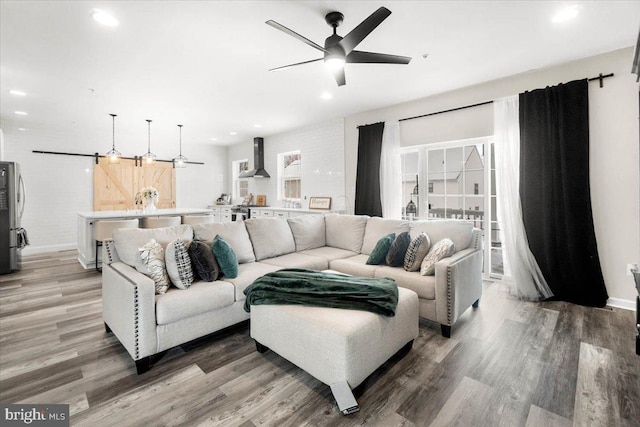 living room featuring ceiling fan, a barn door, and hardwood / wood-style floors