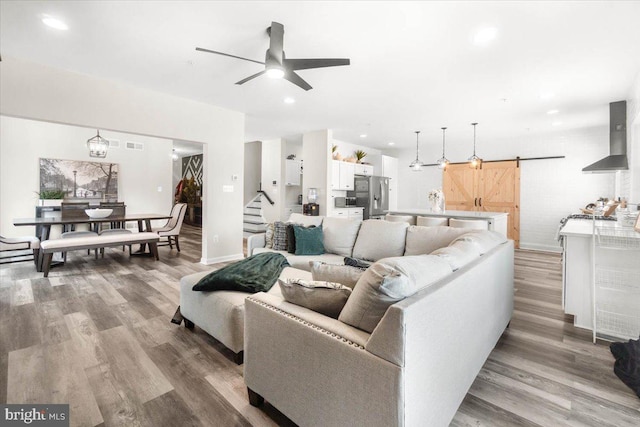 living room featuring light hardwood / wood-style floors, ceiling fan, and a barn door