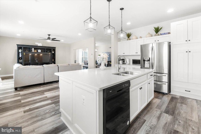 kitchen with hanging light fixtures, sink, white cabinets, a kitchen island with sink, and stainless steel appliances