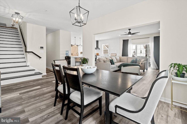 dining area featuring wood-type flooring, sink, and ceiling fan with notable chandelier