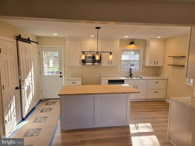 kitchen with butcher block countertops, plenty of natural light, white cabinets, and decorative light fixtures