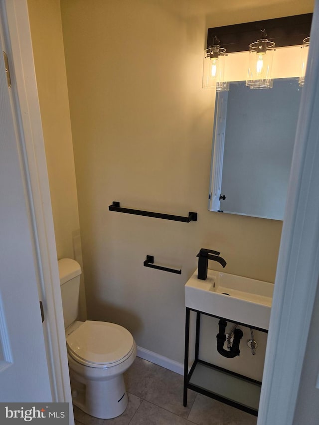 bathroom with toilet, tile patterned floors, and sink