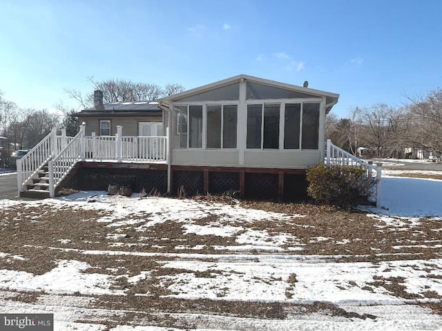 snow covered house with a deck and a sunroom