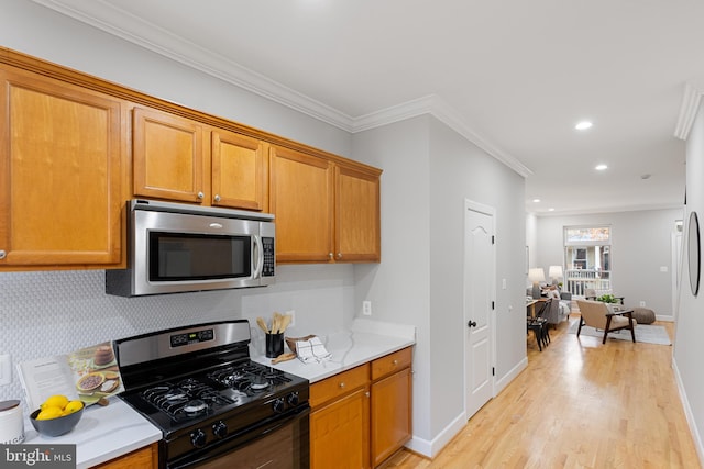 kitchen featuring gas stove, light wood-type flooring, crown molding, and tasteful backsplash