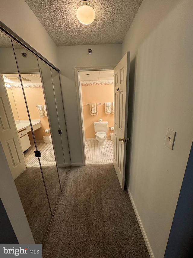 hallway with carpet floors and a textured ceiling