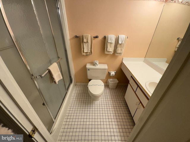 bathroom featuring tile patterned flooring, vanity, toilet, and a shower with door