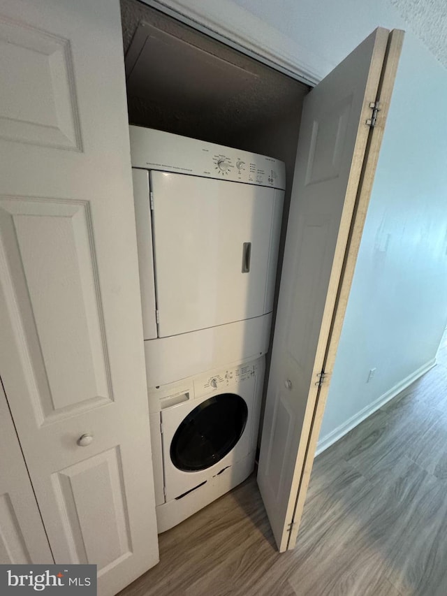 washroom featuring hardwood / wood-style floors and stacked washer and clothes dryer