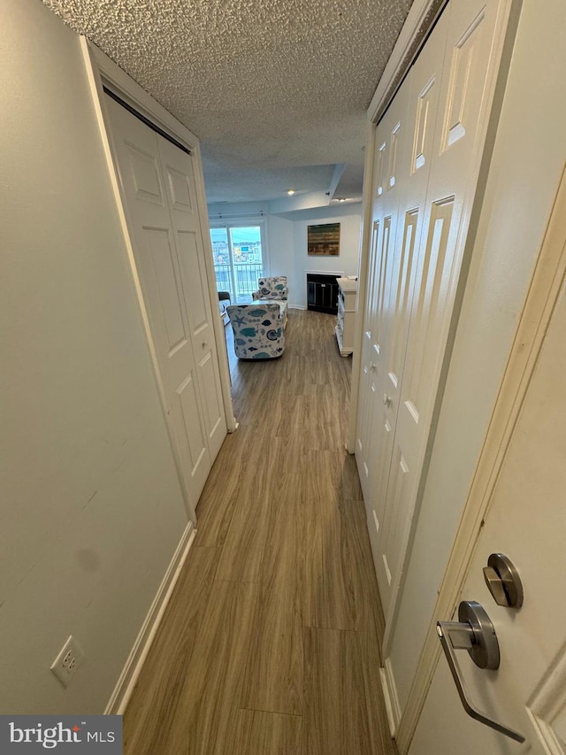 corridor with a textured ceiling and hardwood / wood-style flooring