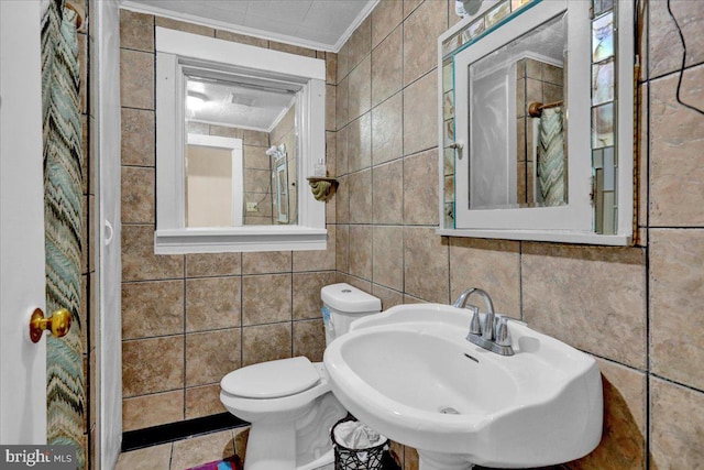 bathroom featuring tile walls, sink, crown molding, and toilet