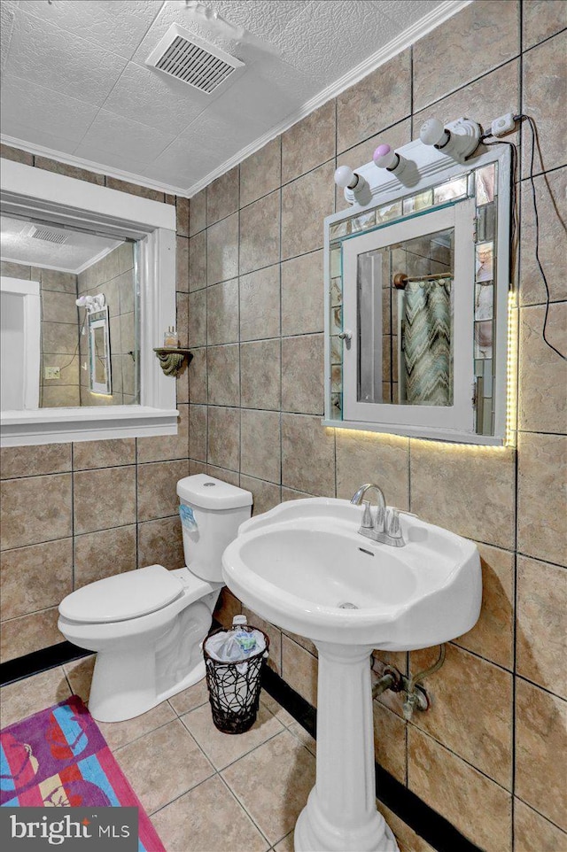 bathroom featuring tile patterned flooring, a textured ceiling, tile walls, and toilet