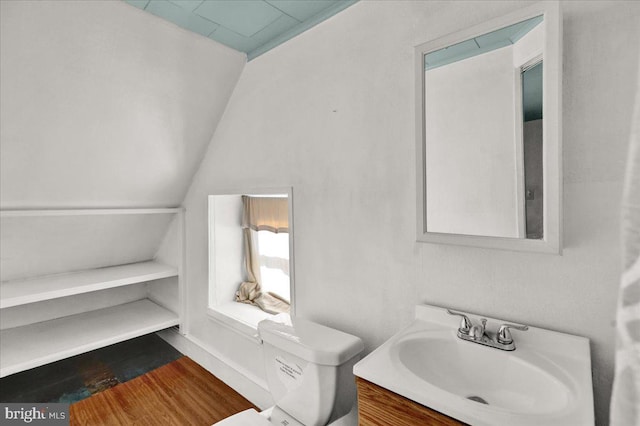 bathroom with hardwood / wood-style flooring, lofted ceiling, vanity, and toilet