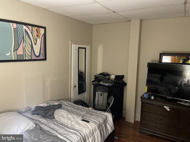 bedroom featuring a drop ceiling and dark wood-type flooring