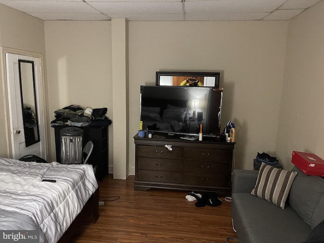 bedroom with a drop ceiling and dark wood-type flooring