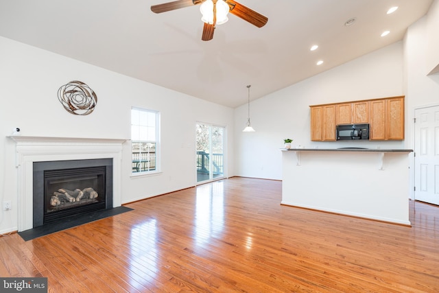 unfurnished living room with ceiling fan, light wood-type flooring, and high vaulted ceiling