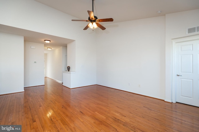 spare room with wood-type flooring, ceiling fan, and a high ceiling