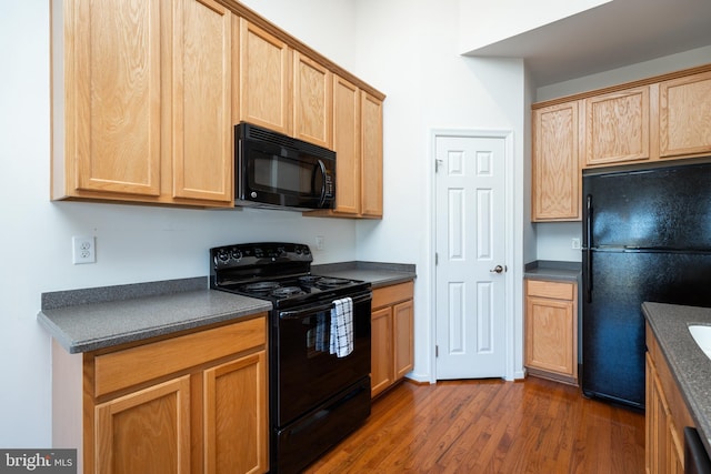 kitchen featuring dark hardwood / wood-style flooring and black appliances