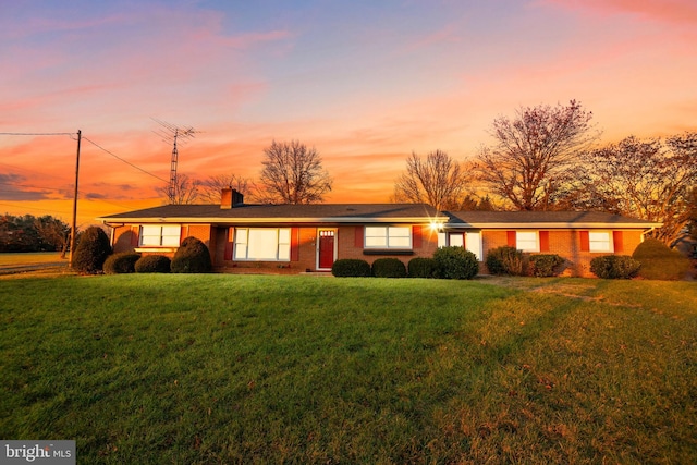 ranch-style home with brick siding and a yard