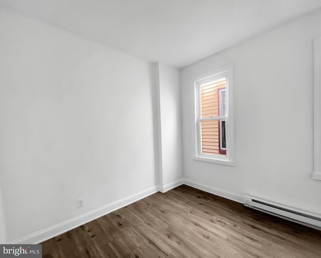 empty room featuring hardwood / wood-style floors and a baseboard radiator