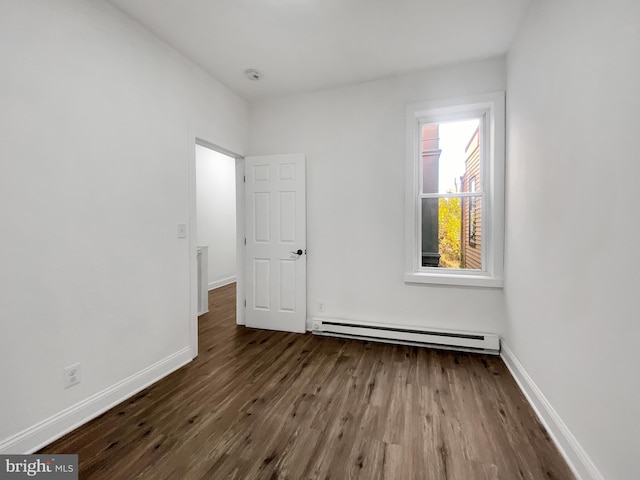 empty room featuring wood-type flooring and a baseboard radiator