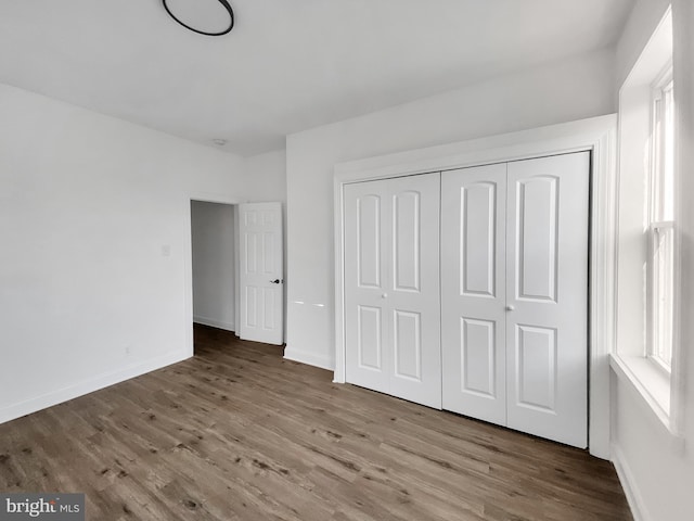 unfurnished bedroom featuring wood-type flooring and a closet