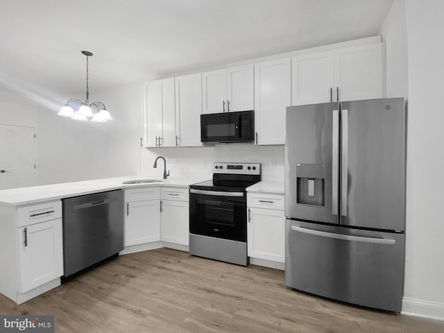 kitchen with appliances with stainless steel finishes, decorative light fixtures, white cabinetry, and sink