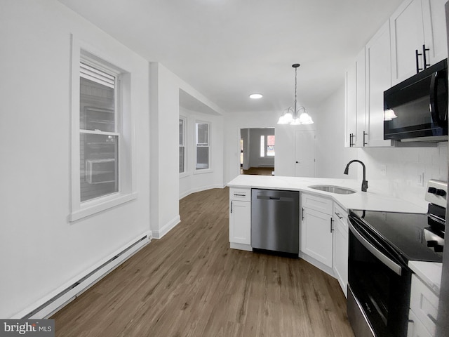 kitchen featuring appliances with stainless steel finishes, sink, a baseboard radiator, white cabinets, and a chandelier