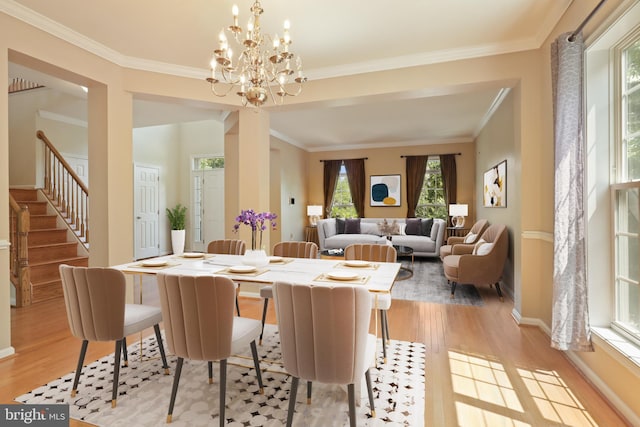 dining room featuring light wood-type flooring, crown molding, and a notable chandelier