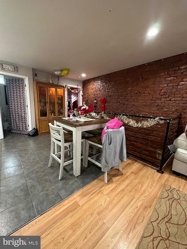 dining space with hardwood / wood-style floors and brick wall