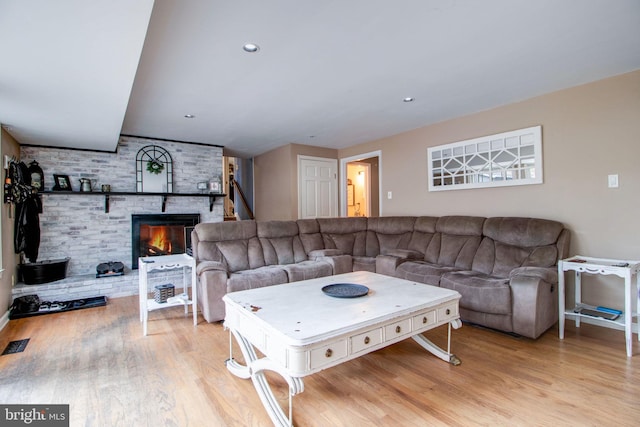 living room featuring light hardwood / wood-style flooring and a brick fireplace