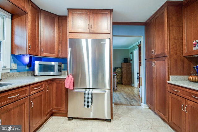 kitchen featuring crown molding, light wood-type flooring, and appliances with stainless steel finishes