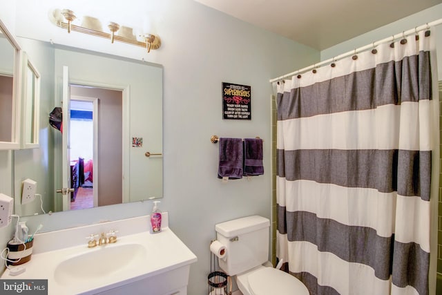 bathroom with curtained shower, vanity, and toilet