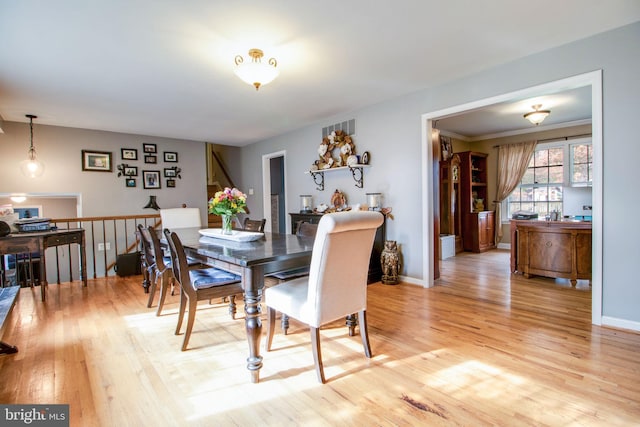 dining area with light hardwood / wood-style floors and crown molding