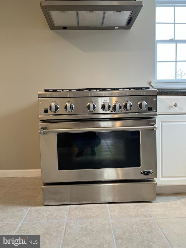 kitchen featuring white cabinetry, exhaust hood, and stainless steel range