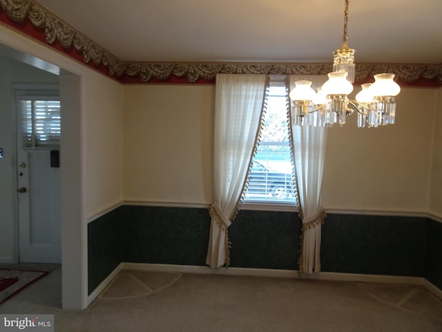 carpeted spare room with an inviting chandelier