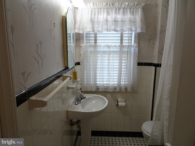 bathroom with tile patterned flooring, tile walls, and toilet