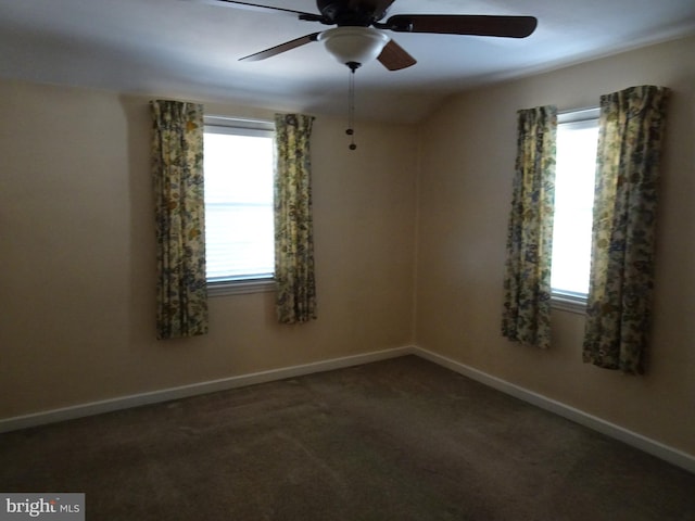 unfurnished room with ceiling fan, dark carpet, and a wealth of natural light