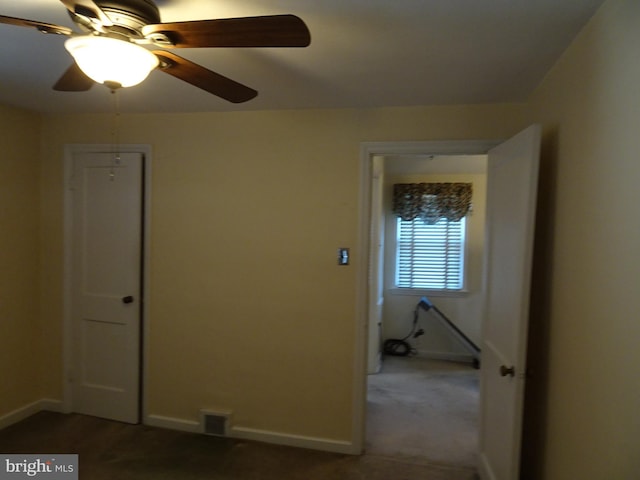 unfurnished room featuring dark colored carpet and ceiling fan