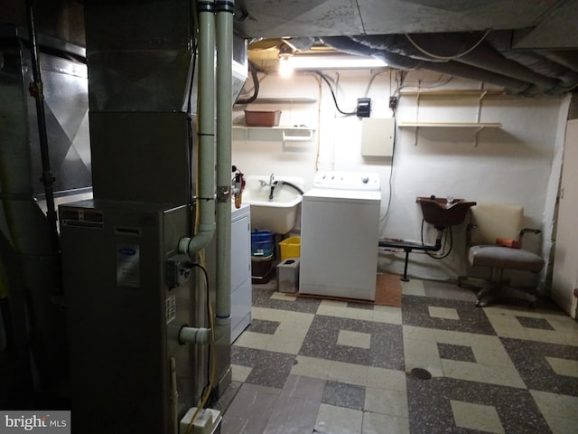 basement featuring heating unit, washer and clothes dryer, and sink