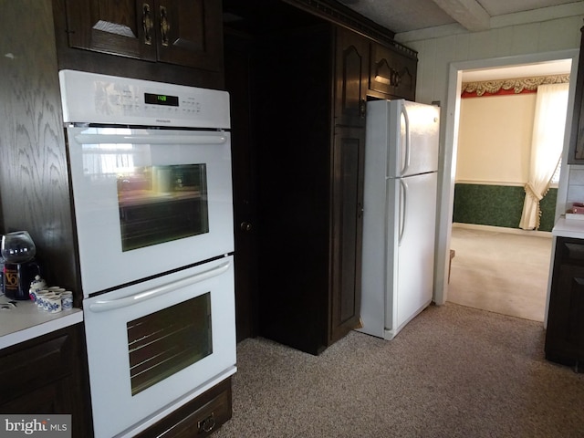 kitchen with light colored carpet, dark brown cabinetry, and white appliances