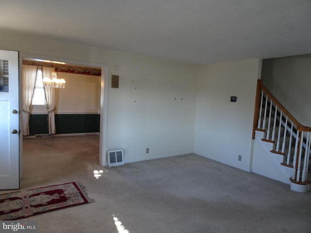 carpeted spare room with a notable chandelier