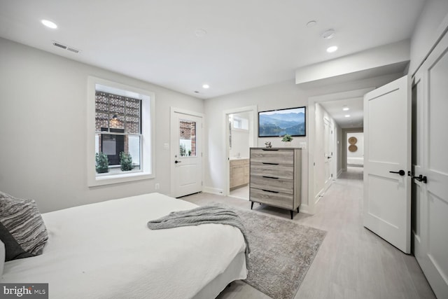 bedroom featuring ensuite bathroom and light hardwood / wood-style flooring