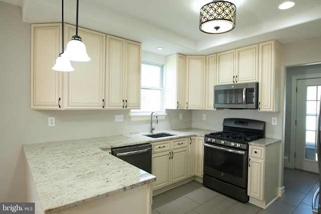 kitchen featuring pendant lighting, sink, light stone countertops, cream cabinetry, and stainless steel appliances